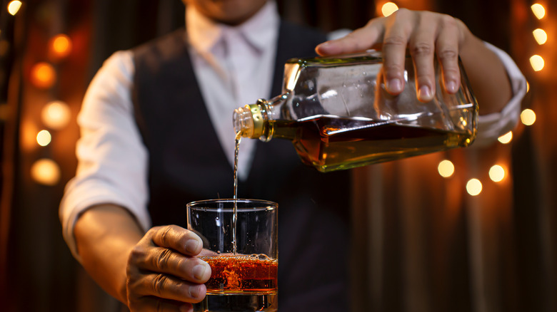 bartender pouring bourbon bottle glass