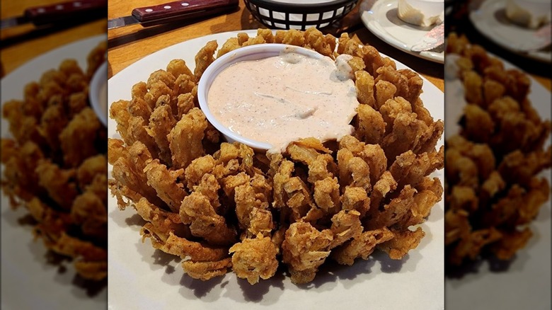 Plate with Cactus Onion appetizer and dipping sauce on table at Texas Roadhouse.