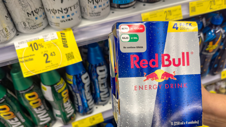 Pack of Red Bull and Monster Energy drinks on store shelf