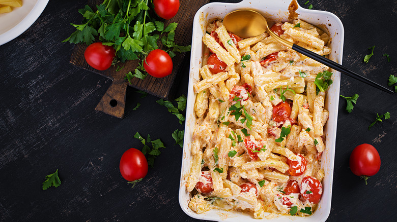penne pasta in baking dish with tomatoes and cheese