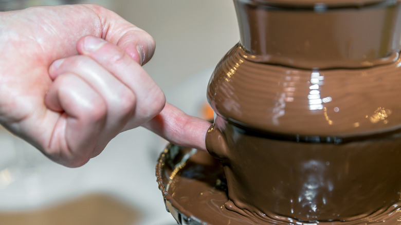 Person dipping a finger in a chocolate fountain
