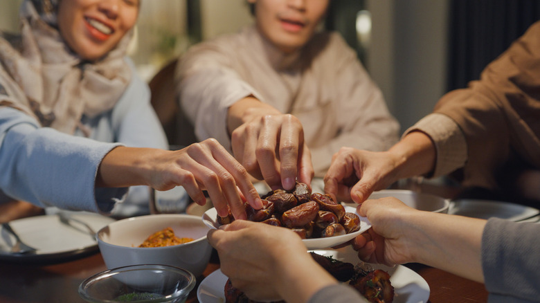 Group of people picking up food from plate with bare hands