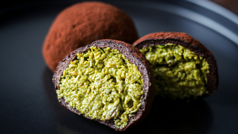 A closeup of chewy Dubai cookie sliced in half, with one whole piece next to it on a black plate