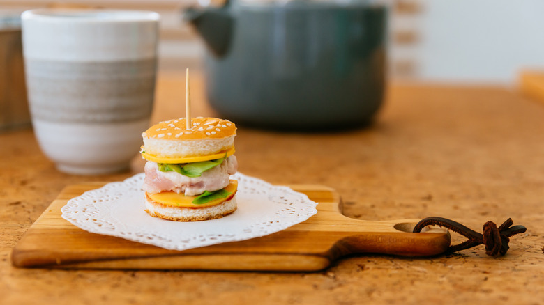 A tiny chicken burger slider on a chopping board