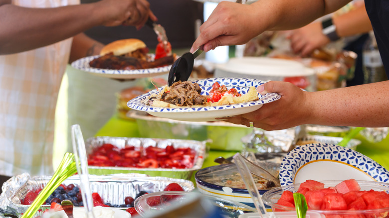 Hands spooning food on plates at a potluck
