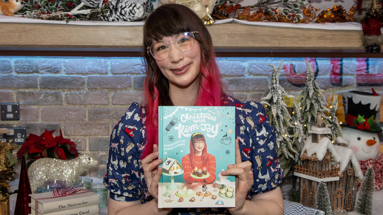 Kim-Joy Hewlett holding her cookbook