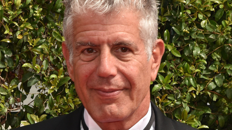 Anthony Bourdain in a tux with a leafy background