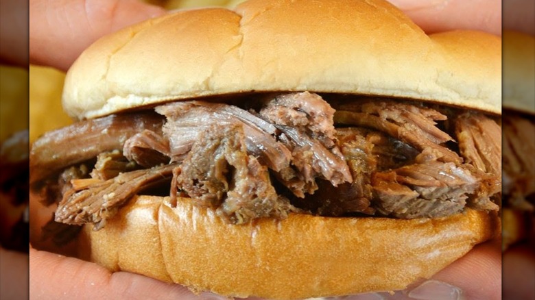 Hands holding Culver's Beef Pot Roast sandwich