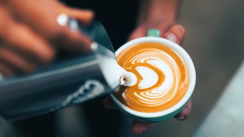 Barista pouring milk in coffee