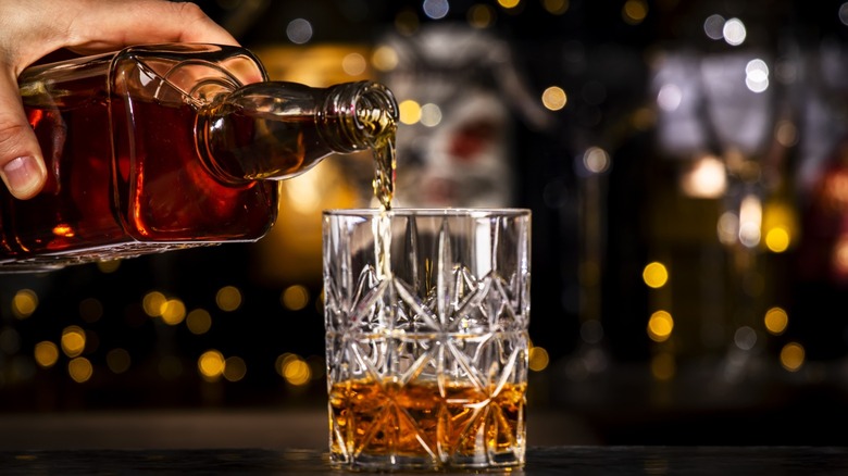 Bartender pouring bourbon into rocks glass