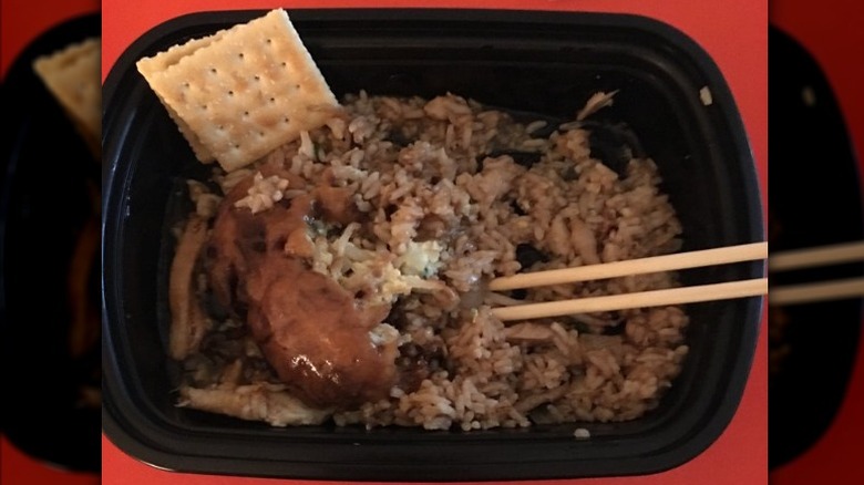 Chicken egg foo young with chicken fried rice in a to-go container with chopsticks sticking out