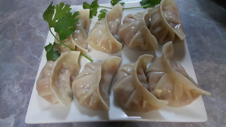 Steamed pork dumplings on a white plate garnished with sprigs of parsley
