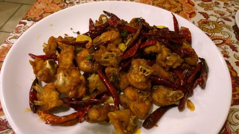 A white plate of chicken with hot pepper