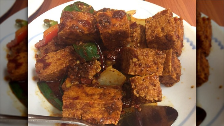 Crispy tofu in numbing oil on a white plate