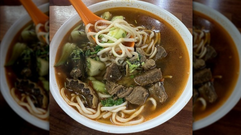 A white bowl of beef noodle soup