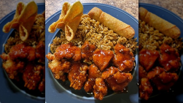 Crab rangoon, egg roll, and pork fried rice with General Tso's Chicken on a blue plate