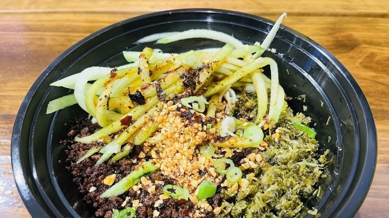 A bowl of dan dan noodles in a to-go container