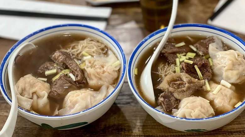 Egg noodle soup with beef brisket in white bowls with blue rims