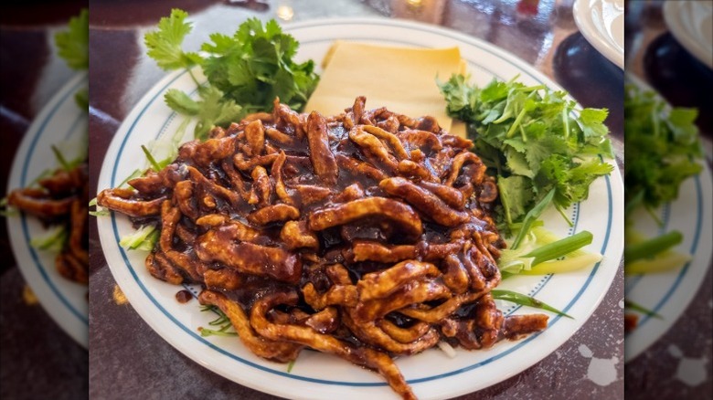 Beijing sauce shredded beef on a white plate with a blue rim