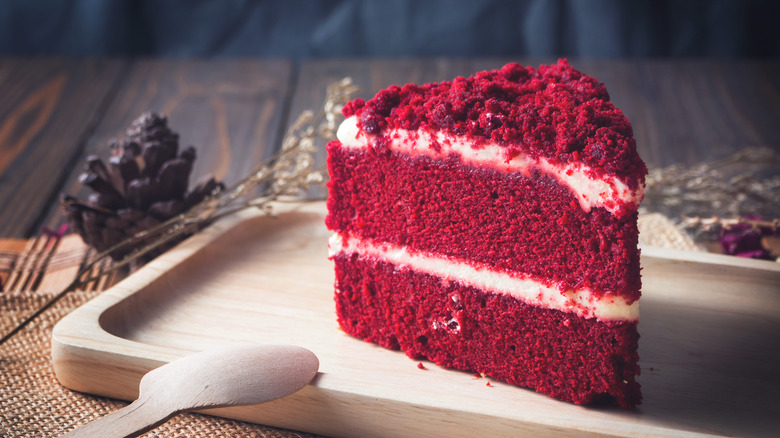 Slice of red velvet cake on wooden board