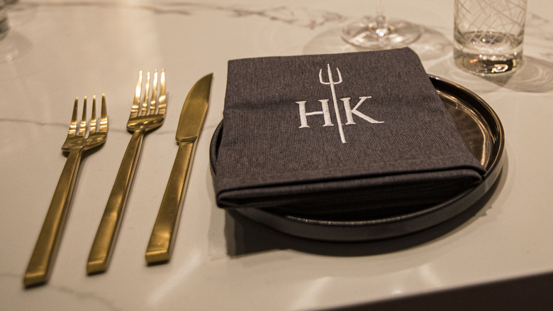 A place setting with a cloth Hell's Kitchen napkin