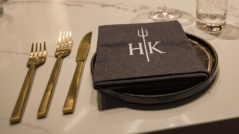 A place setting with a cloth Hell's Kitchen napkin