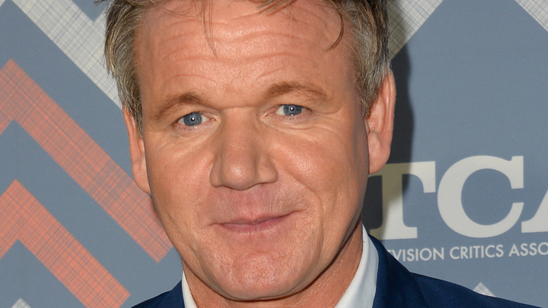 Gordon Ramsay smiles with a white shirt and navy blazer