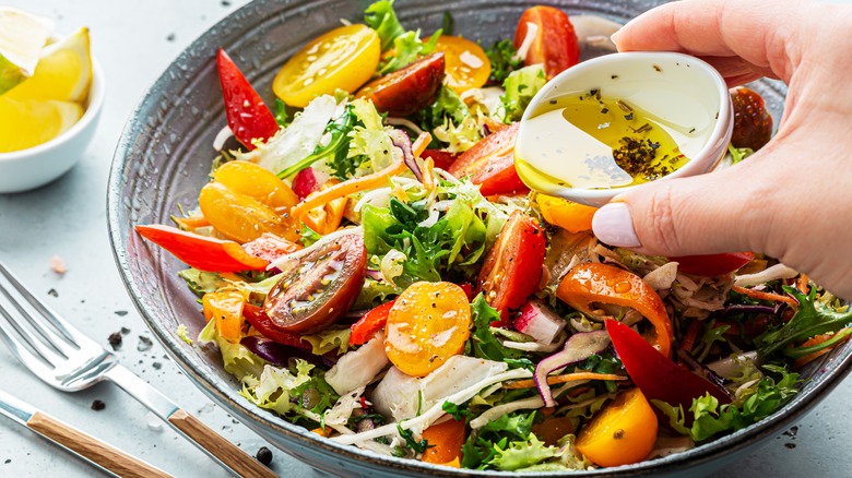 pouring dressing on green salad