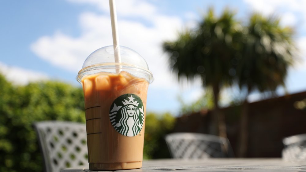 iced starbucks drink on a table with trees in the background