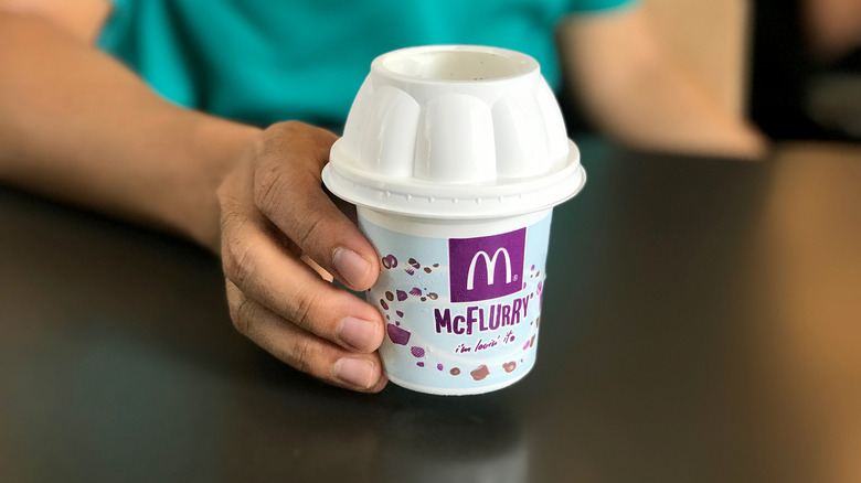 Person in green shirt holding a McFlurry