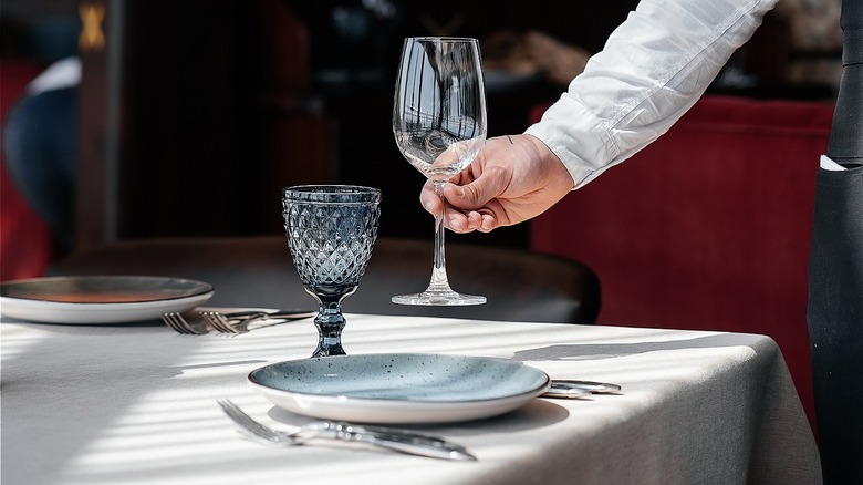 waiter placing wine glass on table