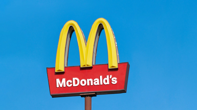 McDonald's golden arches sign against a cloudless blue sky