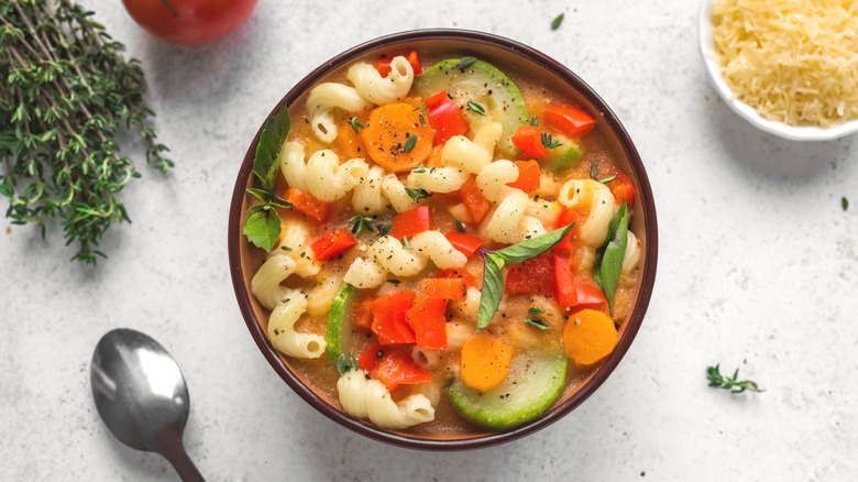 A bowl of minestrone soup in a brown bowl