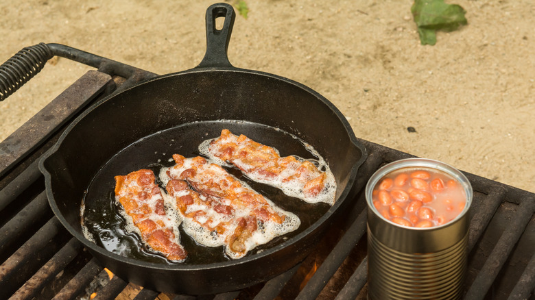 Pan of bacon and can of beans over fire