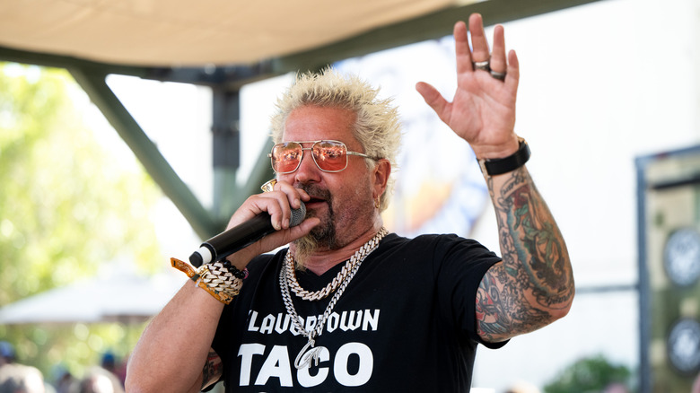 Guy Fieri holding a microphone on stage