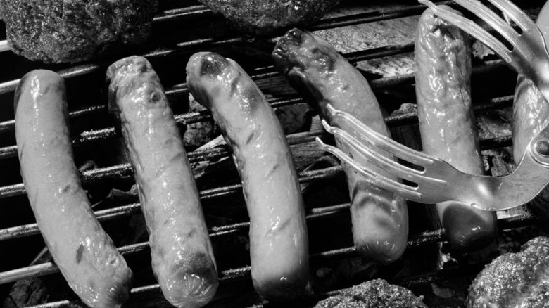 black and white photo of hot dogs on grill