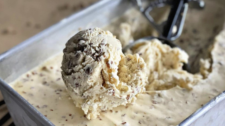 A scoop of Grape-Nuts ice cream being removed from a large container.