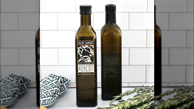 Two bottles of Olio Santo extra virgin olive oil on a kitchen counter.