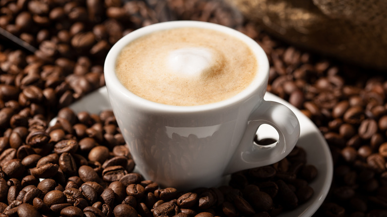 Cappuccino surrounded by coffee beans