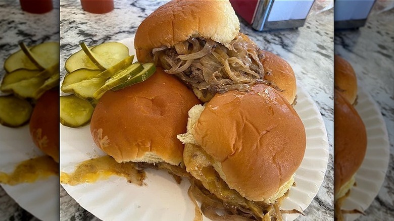 Stack of onion burgers on plate with pickles