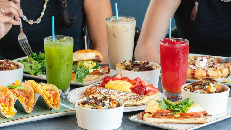 Two people sitting at table full of breakfast foods