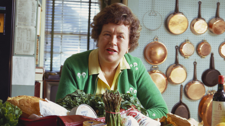 Julia Child with produce and cuts of meat in her kitchen