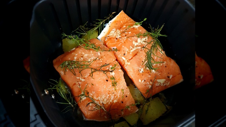 A salmon fillet with fresh herbs on top.