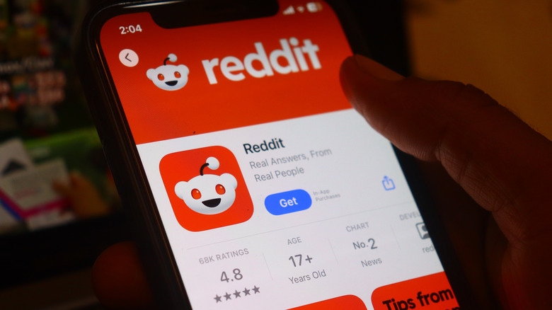 Close-up of phone downloading the Reddit app.