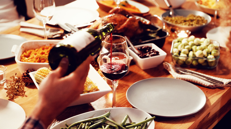 Friendsgiving feast on a table with wine being poured and side dishes