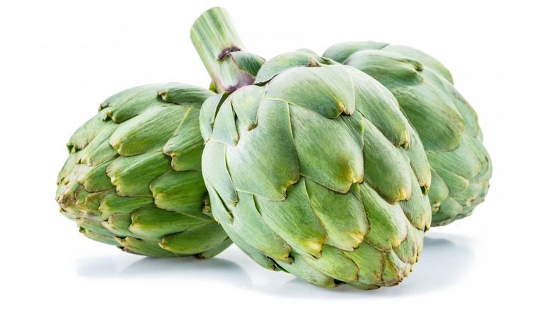 two whole artichokes with white background