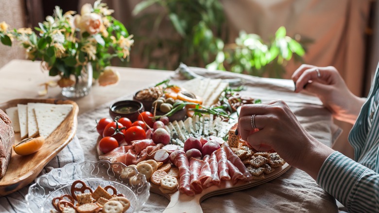person selecting food from charcuterie board