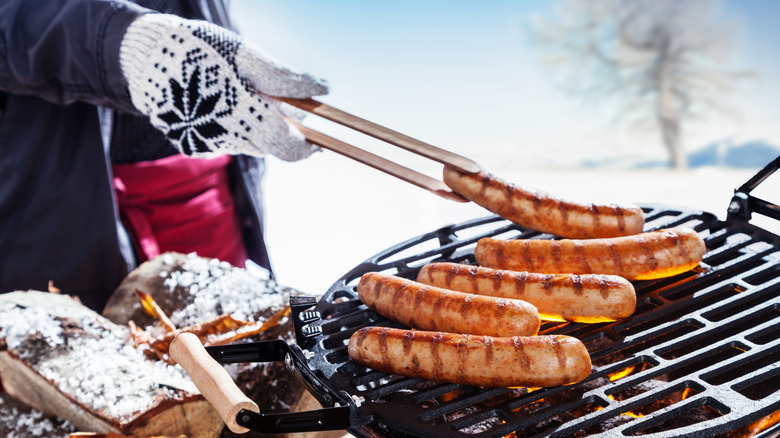 Person wearing gloves grilling outdoors