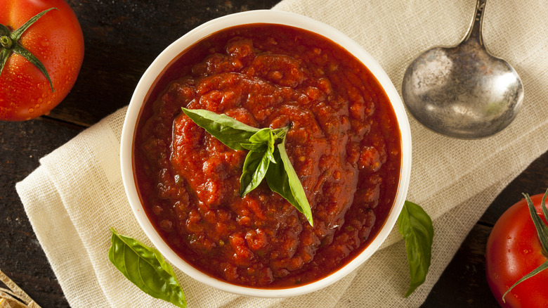 Bowl of marinara sauce near whole tomatoes