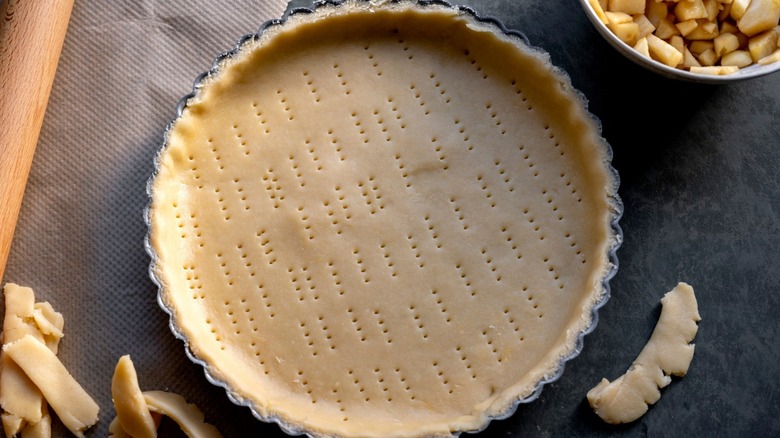 Pie crust in a pan with fork tines poking holes